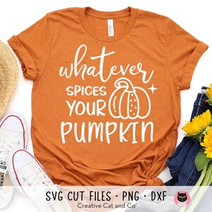 May include: Orange t-shirt with the text "whatever spices your pumpkin" in white. The text is in a handwritten font. A white pumpkin with a stem and seeds is next to the text.