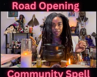 May include: A woman with dreadlocks is seated at a table with a black cauldron, candles, and bottles. The text "Road Opening Community Spell" is displayed in pink neon. The scene suggests a spiritual or ritualistic practice.