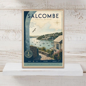 May include: A framed travel poster of Salcombe, South Devon, featuring a coastal landscape with a stone archway, a harbour with boats, a cottage, and a seagull. The text reads SALCOMBE SOUTH DEVON, COASTAL CHARM, and WALK, SAIL, EXPLORE, UNWIND.