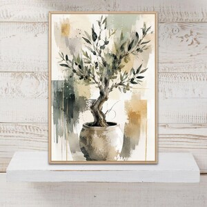 May include: A framed wall art print featuring an abstract watercolour painting of an olive tree in a round ceramic pot. The artwork uses a palette of muted sage green, dark olive, charcoal grey, cream, and metallic gold accents on a textured background.