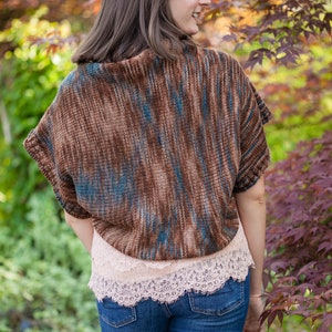 May include: A woman wearing a brown and blue striped knitted top with a lace trim and blue jeans.