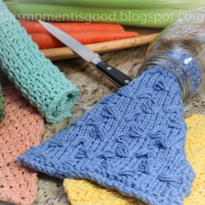 Puede incluir: Un juego de cuatro pa&ntilde;os de cocina de punto en varios colores, incluyendo turquesa, melocot&oacute;n, amarillo y azul. El pa&ntilde;o de cocina azul est&aacute; drapeado sobre un tarro de vidrio.