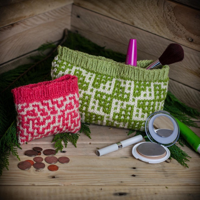 May include: Two knitted cosmetic bags, one pink and one green, with white geometric patterns. The green bag holds a mascara tube and a makeup brush. Coins and makeup items are scattered on a wooden surface.