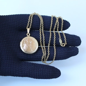 May include: A gold chain necklace with a locket pendant featuring the zodiac sign Aquarius. The locket is engraved with the word "Aquarius".