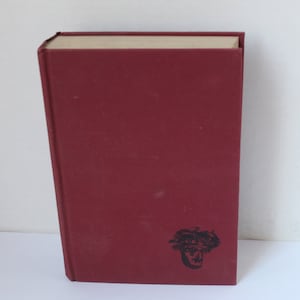 May include: A burgundy hardcover book with a black and white illustration of a plant on the front cover.