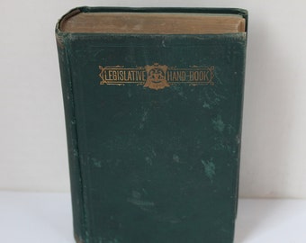 Peut inclure: Un livre relié vert foncé avec une inscription dorée "LEGISLATIVE HAND-BOOK".