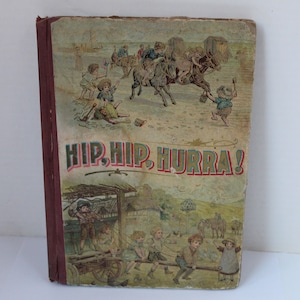 May include: A vintage children's book with a colorful cover featuring children playing on a beach. The book title is "HIP, HIP, HURRA!" and the cover depicts children riding horses, playing with toys, and pulling a wagon.