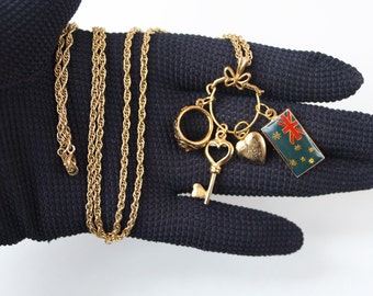 Collier porte-breloques vintage des années 1980 avec breloques, breloque médaillon coeur, breloque clé, breloque bague classe, drapeau australien sur une longue chaîne en plaqué or de 22 po.