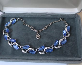 Collier vintage CORO des années 1950, orné de faux saphirs bleus et de métal argenté. Longueur ajustable.