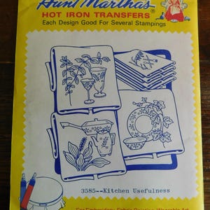 May include: A yellow and white Aunt Martha's Hot Iron Transfers packet titled 3585--Kitchen Usefulness. The cover features blue line art illustrations of kitchenware, glassware, and foliage designs intended for embroidery and fabric painting.