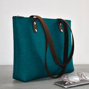 Merino wool felt shoulder bag with linen lining, secure zipper closure, one interior zipper pocket and leather straps