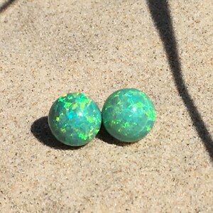 May include: Two green opal earrings with a shimmery, iridescent finish.