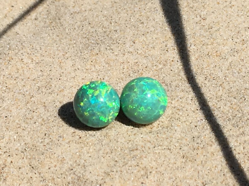 May include: Two green opal earrings with a shimmery, iridescent finish.