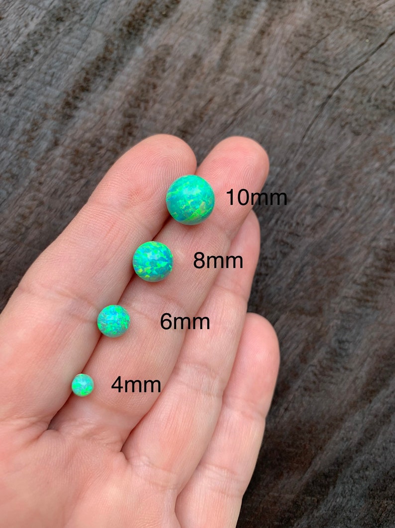 May include: Four opal cabochons in different sizes, 4mm, 6mm, 8mm, and 10mm. The opals are a light green color with a white and yellow iridescent sheen.
