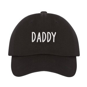 May include: Black baseball cap with white embroidered text that reads "DADDY".