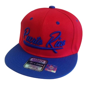 May include: A red and blue baseball cap with the text "Puerto Rico" in blue embroidery on the front.