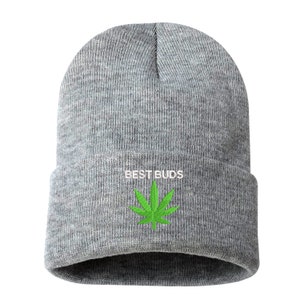 May include: A gray beanie with the embroidered text "BEST BUDS" in white above a green cannabis leaf. The beanie is made of a soft, knitted material.