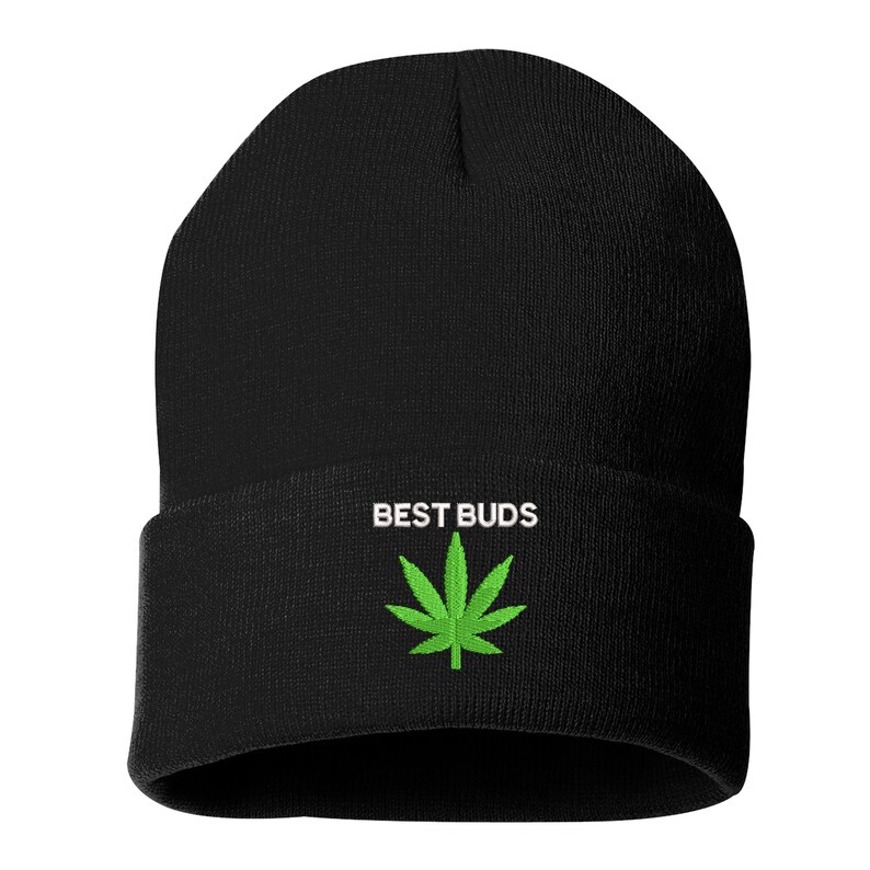 May include: Black beanie hat with the text "BEST BUDS" in white above a green cannabis leaf. The hat is made of a soft, knitted material and has a folded cuff.