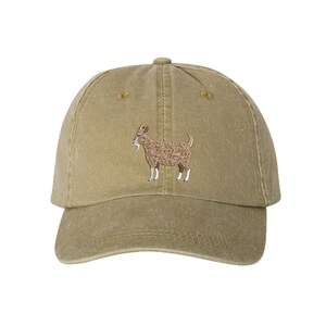 May include: A brown and beige baseball cap with an embroidered image of a brown goat on the front.