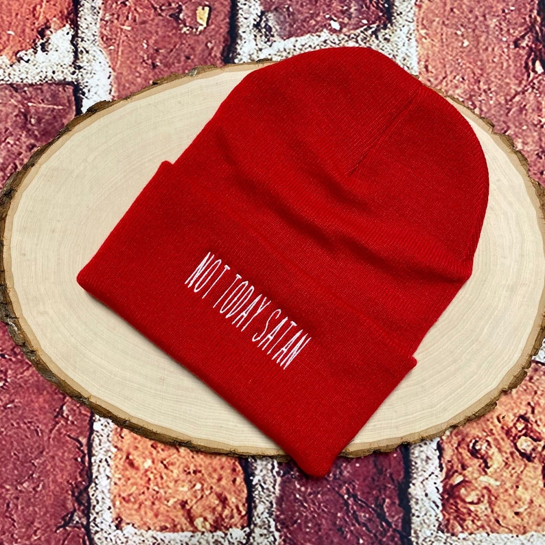 May include: Red knitted beanie with the phrase "Not Today Satan" embroidered in white.
