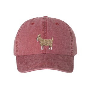 May include: A red, vintage-style baseball cap with an embroidered image of a brown goat.