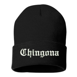 May include: Black beanie hat with the word "Chingona" embroidered in white, gothic-style lettering across the folded brim. The hat is made of a soft, knitted material.