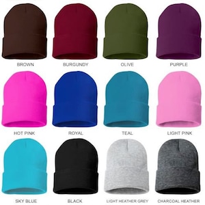 May include: A collection of beanies in various colors, including forest green, red, navy, and camo. Other colors include brown, burgundy, olive, purple, hot pink, royal, teal, light pink, sky blue, black, and gray.