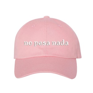 May include: A pink baseball cap with the phrase "no pasa nada" embroidered in white on the front.