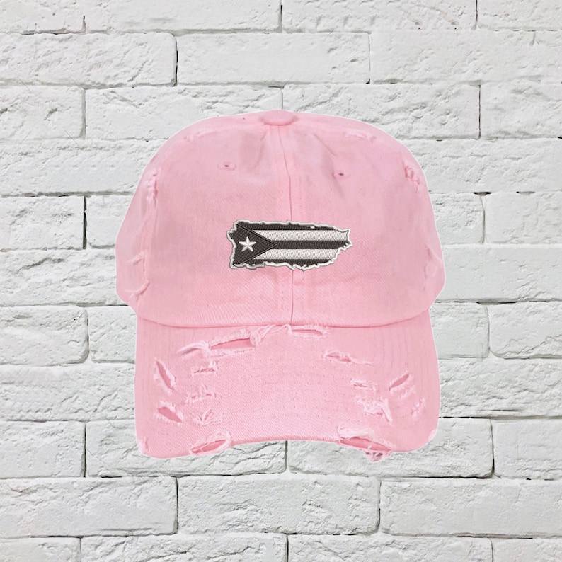 May include: A pink distressed baseball cap with a white star and black and white Puerto Rican flag patch.