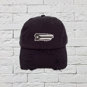 May include: A black distressed baseball cap with a white and gray embroidered Puerto Rican flag.