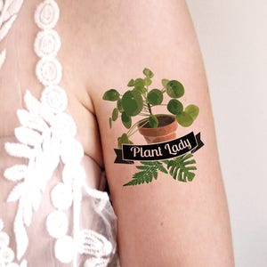 May include: A temporary tattoo featuring a potted plant with the text "Plant Lady" on a black ribbon.