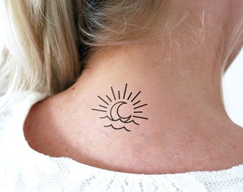 May include: A simple line drawing tattoo of a sun and moon over a wavy line, representing the ocean, on a person's neck.