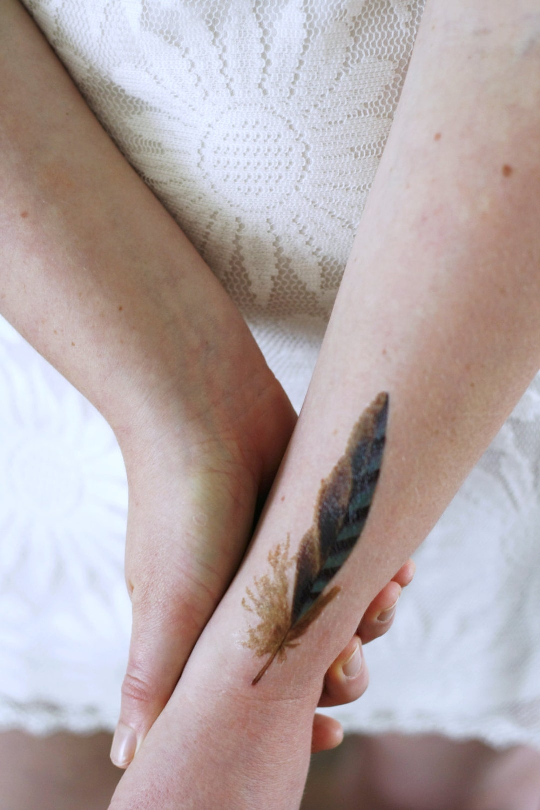 Fine line feather tattoo on the inner forearm