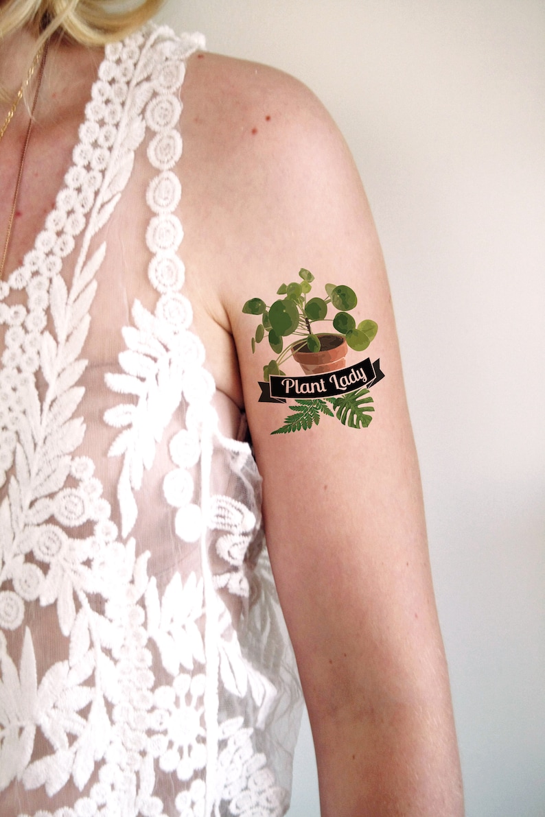 May include: A temporary tattoo featuring a potted plant with the text "Plant Lady" on a black ribbon.