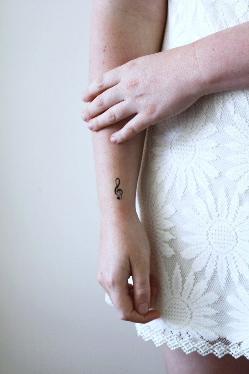 Puede incluir: Primer plano de un brazo con un peque&ntilde;o tatuaje de clave de sol en la mu&ntilde;eca.