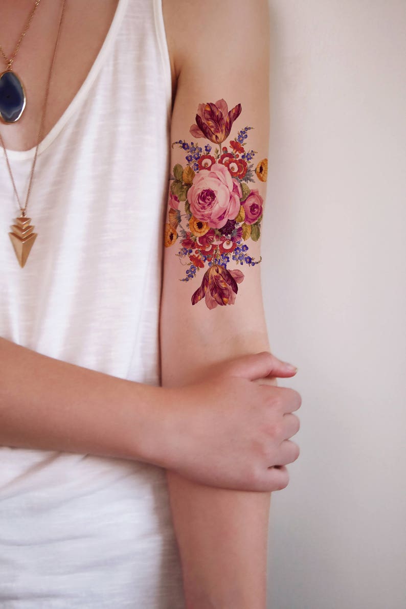 May include: A temporary tattoo featuring a colorful floral bouquet with a large pink rose in the center. The bouquet includes various flowers in shades of pink, red, yellow, and blue.
