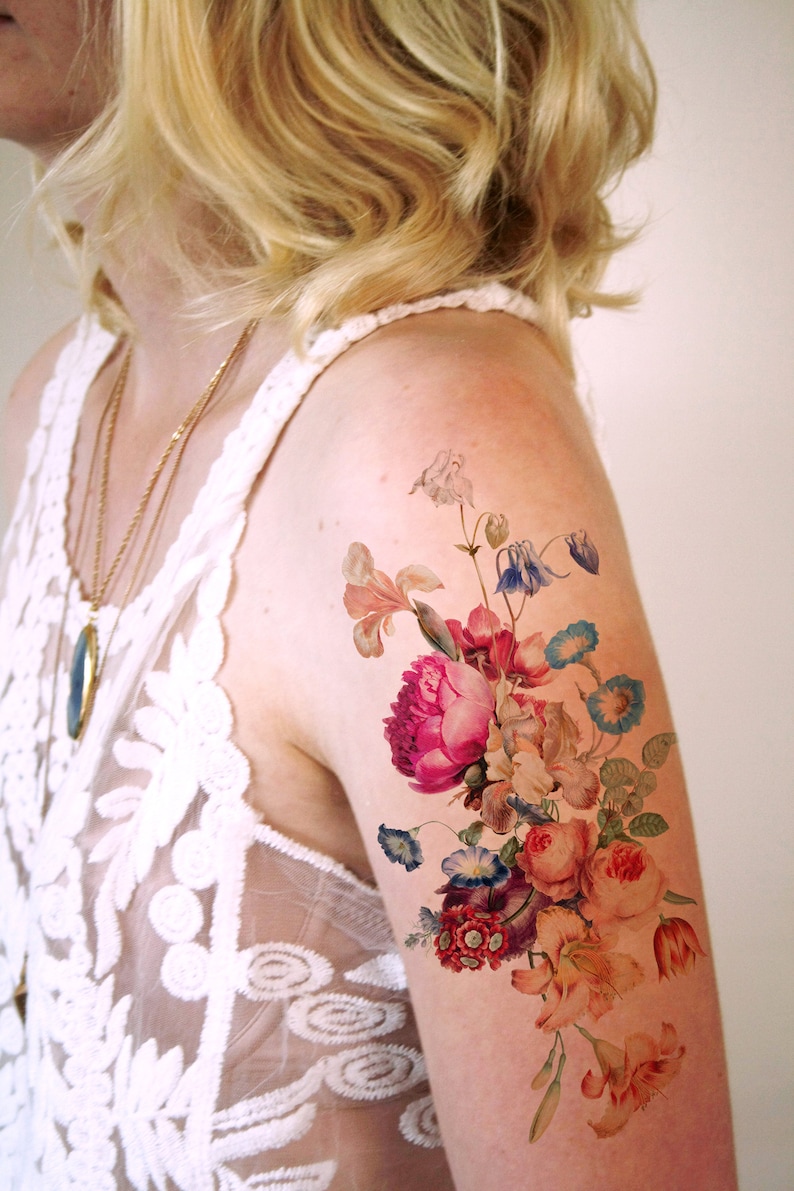 May include: A temporary tattoo featuring a colorful bouquet of flowers, including pink peonies, orange lilies, and blue forget-me-nots.
