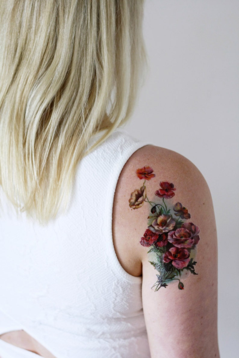 May include: A temporary tattoo featuring a bouquet of red, pink, and white flowers with green leaves. The flowers are arranged in a cluster and have a vintage style.