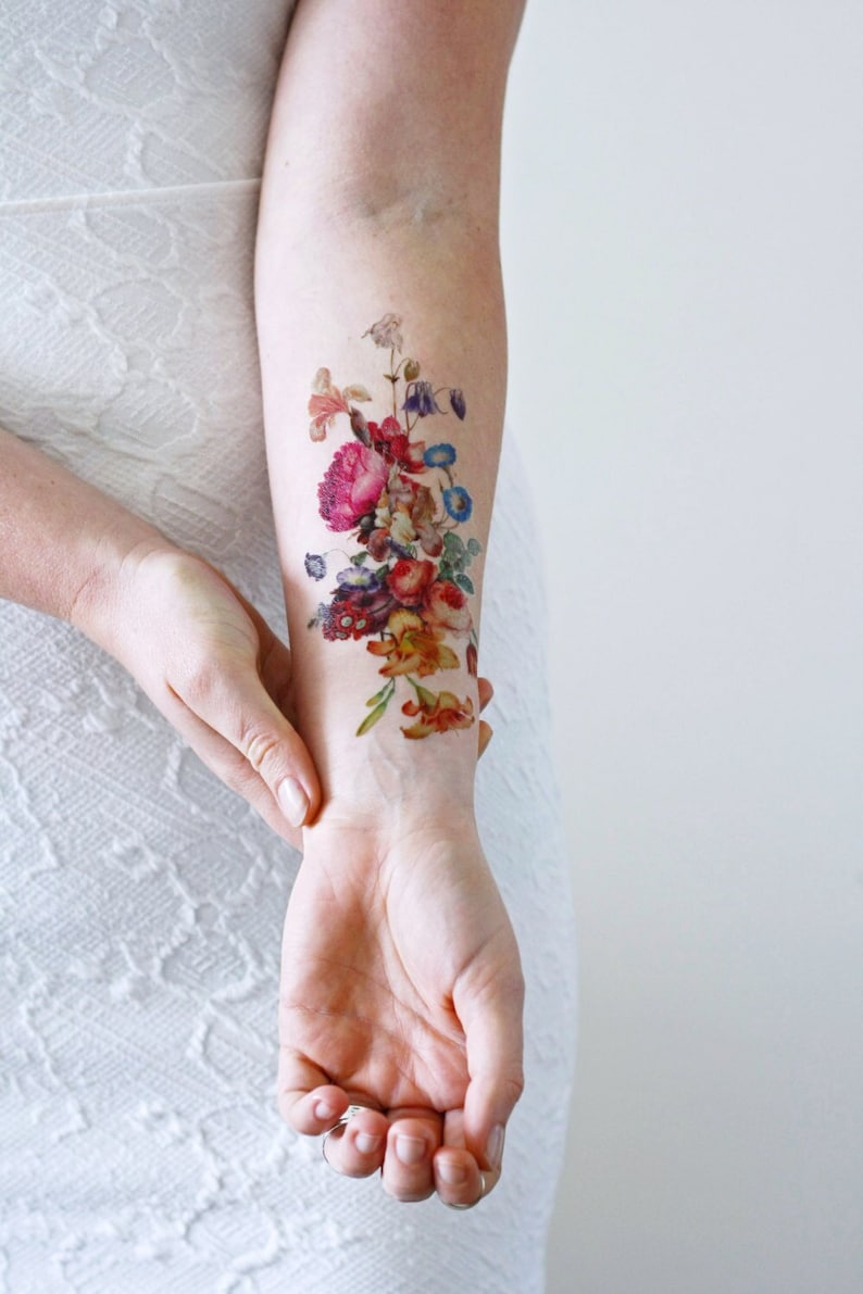 May include: A temporary tattoo featuring a colorful bouquet of flowers in a vintage style. The tattoo is applied to a person's arm.