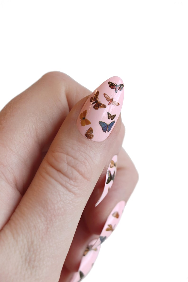 May include: Pink nail polish with butterfly decals. The butterflies are in various colors and patterns.