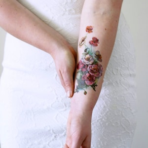 May include: A temporary tattoo featuring a bouquet of red, pink, and white flowers with green leaves. The flowers are arranged in a cluster and have a vintage style.