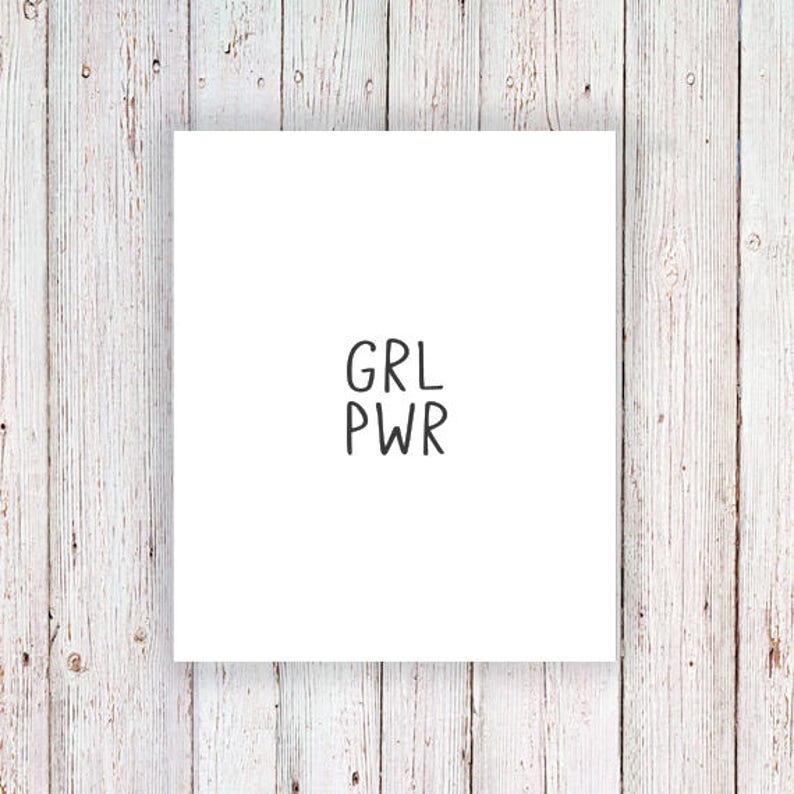 May include: White card with the text "GRL PWR" written in black.