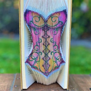 May include: A white ceramic mug with a black handle and the text "But First, Coffee" in a black, handwritten-style font. The mug is on a white surface.