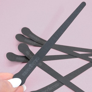 以下が含まれることがあります： 丸みを帯びたエッジと「REINVENTED」という文字が印刷された黒い爪やすりのセットです。