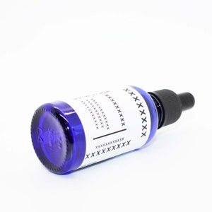 May include: A deep blue glass bottle with a black dropper. The bottle features a white label with black text and a black line. The base of the bottle is marked with "30ml".