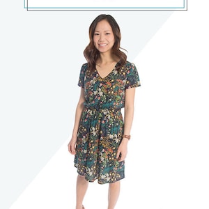 May include: A woman wearing a floral print dress with a V-neck and short sleeves. The dress has a cinched waist and a knee-length skirt. The text "AMALFI DRESS 2-22" is displayed at the top of the image.