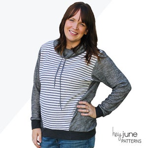 May include: A woman wearing a gray and white striped hoodie with a cowl neck. The hoodie has a gray panel on the side. The text "HALIFAX HOODIE XS - 2XL hey june PATTERNS" is visible on the image.