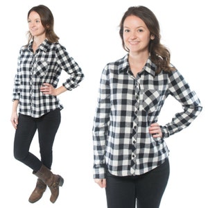 May include: A black and white plaid flannel shirt with long sleeves and a button-down front. The shirt has a chest pocket and is worn with black jeans.