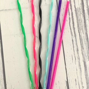 May include: A collection of six colorful, reusable plastic drinking straws. The straws are green, pink, black, light blue, purple, and pink. Each straw has a spiral design and is approximately 9 inches long.
