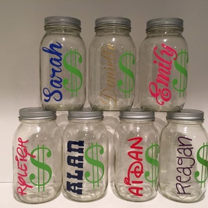 Pu&ograve; includere: Sette barattoli di vetro trasparente con coperchi argentati, ognuno con un nome personalizzato e un adesivo a forma di dollaro. I nomi sono: Sarah, Danielle, Emily, Ryliegh, Alan, Aidan e Reagan.